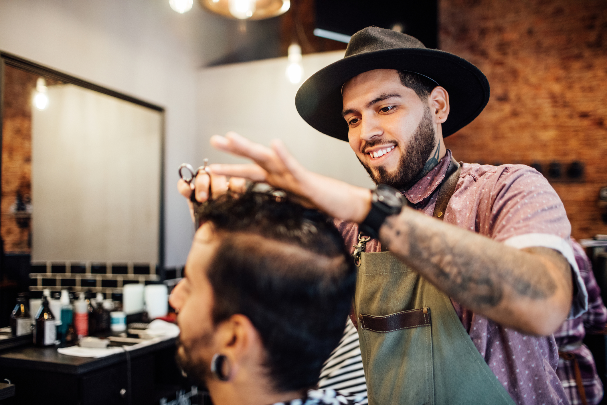 Smiling barber cutting customer's hair in salon