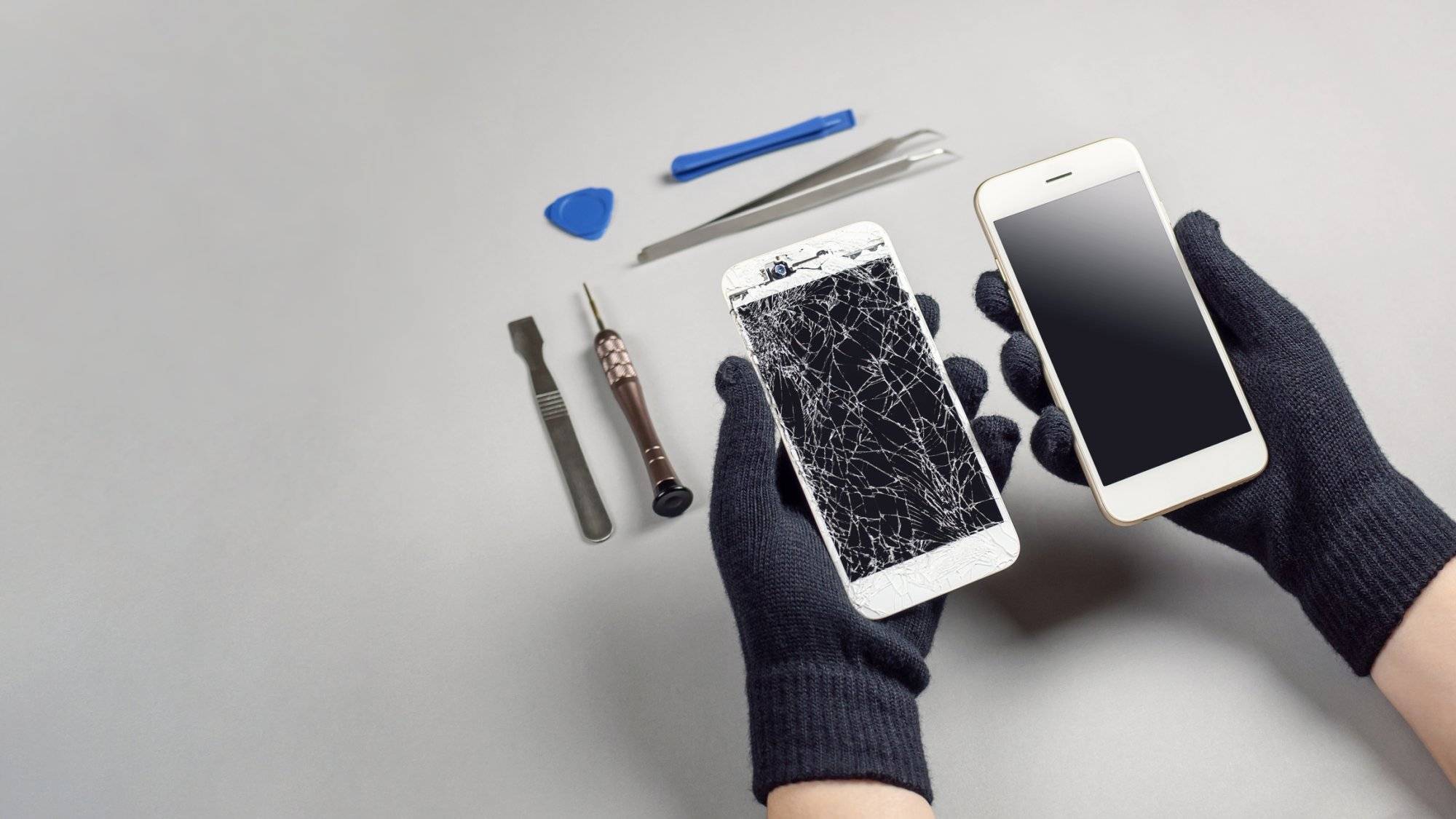 Technician repairing broken smartphone on desk