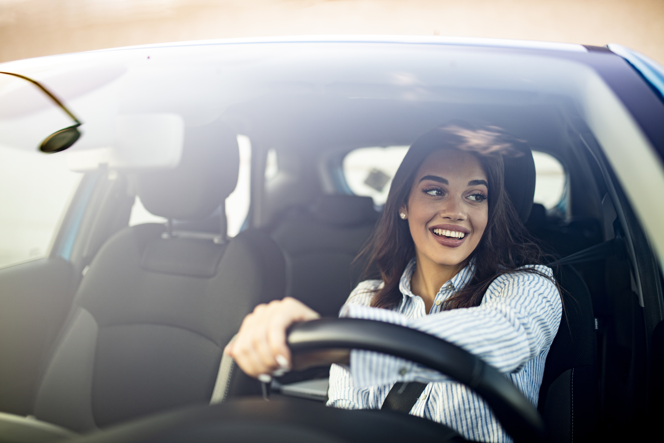Cute young success happy brunette woman is driving a car.